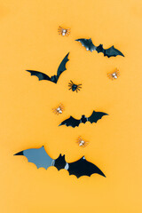 Vertical Halloween composition with black decorative bats over orange background. Minimal Halloween concept