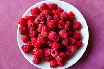 a white plate with raspberries on the table. 