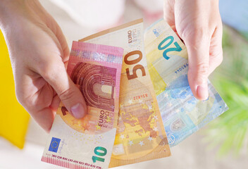 Hands hold different euro banknotes and euro coins. State aid in times of crisis to compensate for...