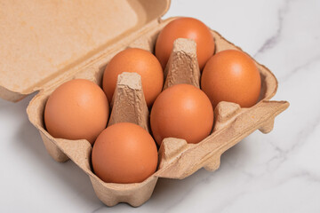A cardboard box full of fresh chicken eggs on a white background.