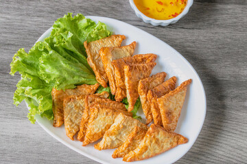 Triangular fried tofu eating with spicy dipping sauce, sweet and spicy