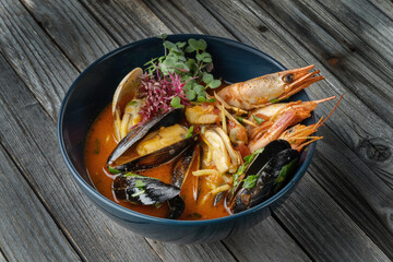 Hot Tom Yum soup with shrimps, various shellfish and microgreens.