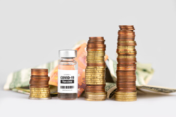 Vial glass bottle of COVID-19 vaccine standing next to money coin stack. SARS - CoV2 vaccination concept. Vaccine against coronavirus. Money behind a vaccine procurement. 