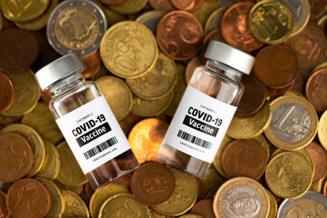 Vial glass bottle of COVID-19 vaccine standing on euro coins. SARS - CoV2 vaccination concept....
