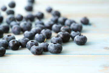 Ripe and juicy fresh blueberries are scattered on a wooden table. Selective focus. Close-up. Copy space. Concept seasonal berries, healthy organic food