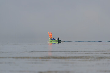 Fishing boat returning from the sea in foggy weather on calm water of Szczecin Lagoon in Poland.