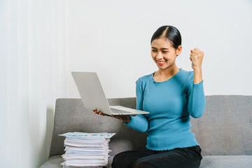 Smile asian business woman using laptop while sitting on couch at home.