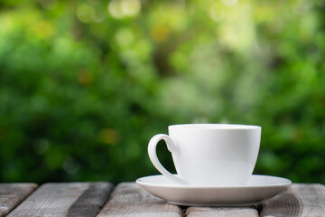 Hot Coffee Drink Concept, Hot ceramic white coffee cup with smoke on an old wooden table in a natural background.