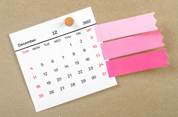 The December 2022 calendar with blank adhesive note paper on brown background.