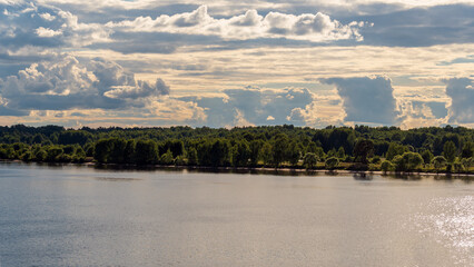 Obraz premium Landscape with a river and a forest illuminated by the setting sun. 