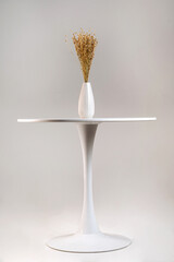 Dry flower bouquet in a white modern vase on a wooden table. Place for text, copy space.