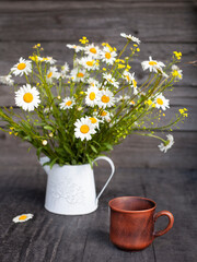 a bouquet of daisies and a mug stand on a black surface