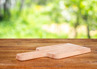 cutting board on wooden table outdoors with garden background
