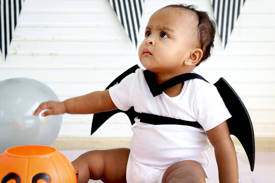 Adorable African Baby Kid Dressing Up In Vampire Fancy Halloween Costume With Black Bat Wings, Cheerful Little Cute Child Go To Party, Playing Trick Or Treat, Happy Halloween Celebration.