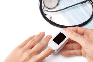 Woman hand holding pulse oximeter on finger to measuring saturation oxygen level and pulse rate on white background.