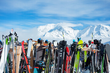 Many skis stand on alpine resort over mountain summits