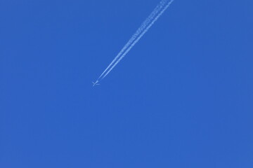 High altitude aircraft creates contrails in the clear blue sky