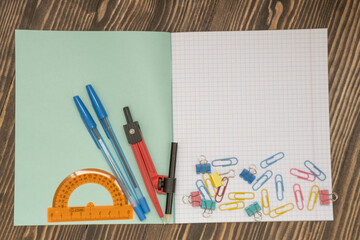 notebook ,compass , protractor on a wooden background, concept coming to school soon