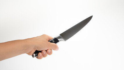 A woman's left hand holds a kitchen knife blade diagonally upwards