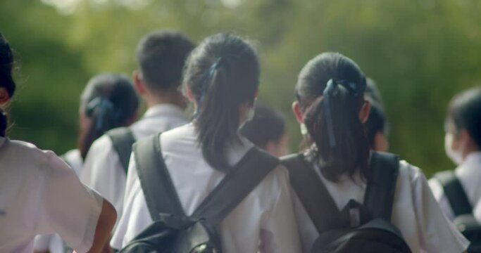 Slow motion back view of the Asian high school students in white uniform are going back to school when school starts.	