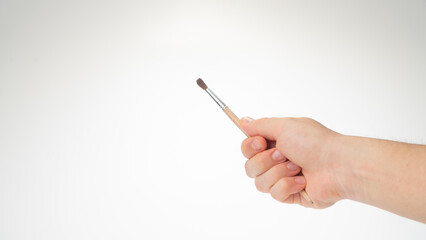 A woman's right hand holds a brush for drawing, gesture to draw