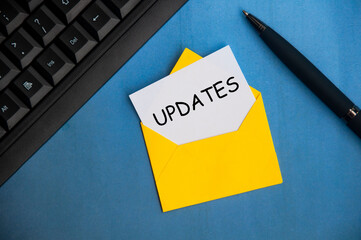 Updates text on a piece of paper in an envelope. With keyboard and pen on blue background.