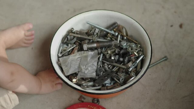 lots of different screws, bolts, grommets and fasteners crews, nuts old and used lying in metal bowl. child hands male hands choosing, grabbing, searching one in pile stack.