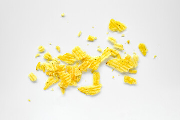 Rippled chips crumbs, scattered potato snack pieces isolated on white background, top view.