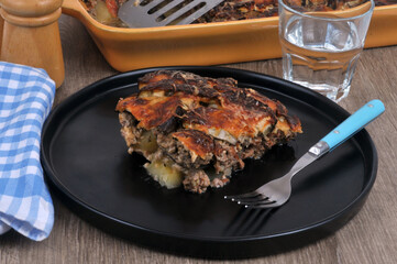 Assiette de moussaka avec une fourchette servie sur une table avec un verre d'eau