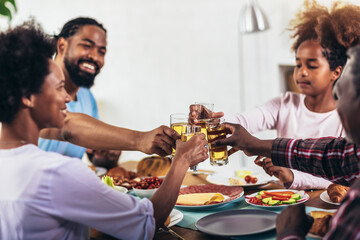 A multi-generational African-American family enjoying food at their dinner table.