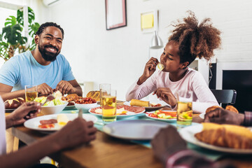 A multi-generational African-American family enjoying food at their dinner table.