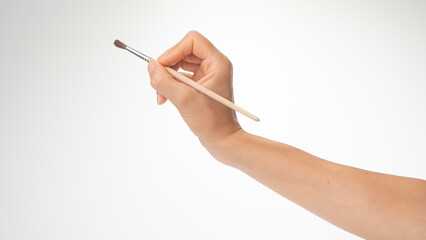 Drawing brush in a woman's right hand, gesture to draw on a white background