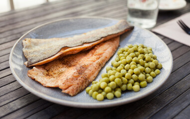 Fried trout fillets served with green peas