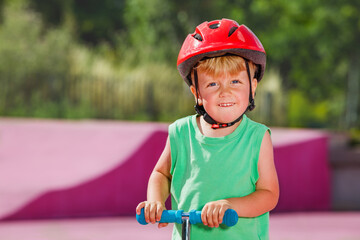 Close portrait small boy on the kick scooter ride and big smile