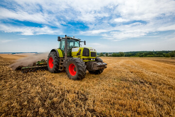 Obraz premium Tractor working in wheat field. Agriculture background. Harvest season