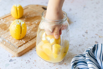 Making preserved Moroccan lemon with lemons and salt. Hand pressing lemons down into jar to squeeze...