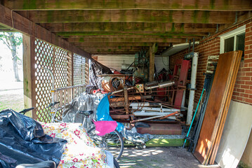 Garage that is dirty, full of garbage, various materials, old stuff, rummage, furniture and mess.