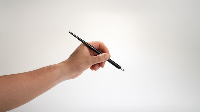 men's left hand holds a calligraphy pen on a white background, gesture drops into the inkwell, lefty
