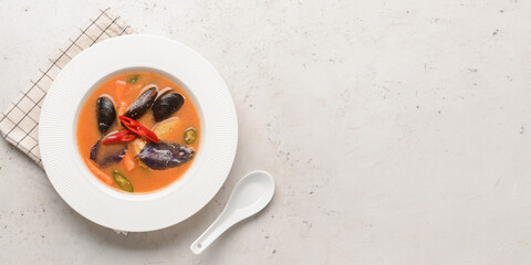 Bowl of spicy Thai soup on light background with space for text