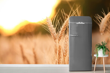 Stylish retro fridge near wall with print of wheat field