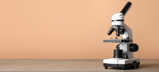 Modern microscope on table against color background with space for text