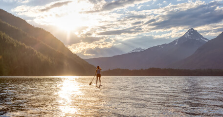 Adventurous Woman Paddle Boarding in a Lake around Canadian Mountain Landscape. Chilliwack Lake,...