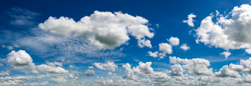 Panoramic vivid blue sky with white clouds.Panorama Sunlight with blue sky on dark background.Vivid sky on white cloud. © noon@photo