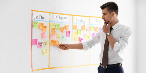 Businessman near scrum task board with stickers in office