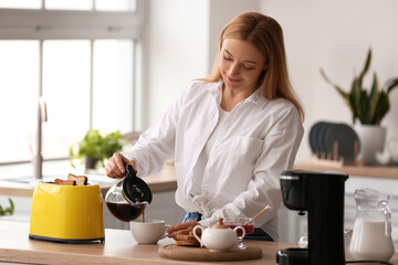 Mature woman making tasty toasts and drinking coffee in kitchen