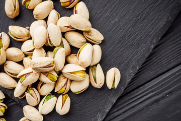 fresh salted pistachios on a black stone wooden rustic background