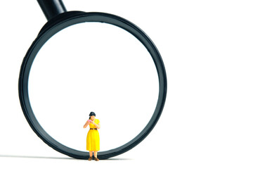 Miniature people toy figure photography. A women student standing in front of magnifier glass, isolated on white background