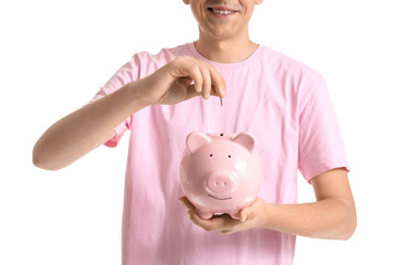 Young man putting coin into piggy bank on white background