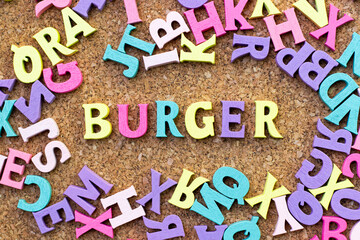 Color alphabet in word burger with another letter as frame on cork board background