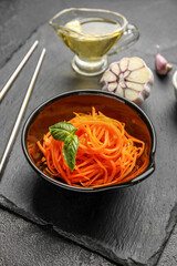 Bowl with spicy carrot salad on dark table